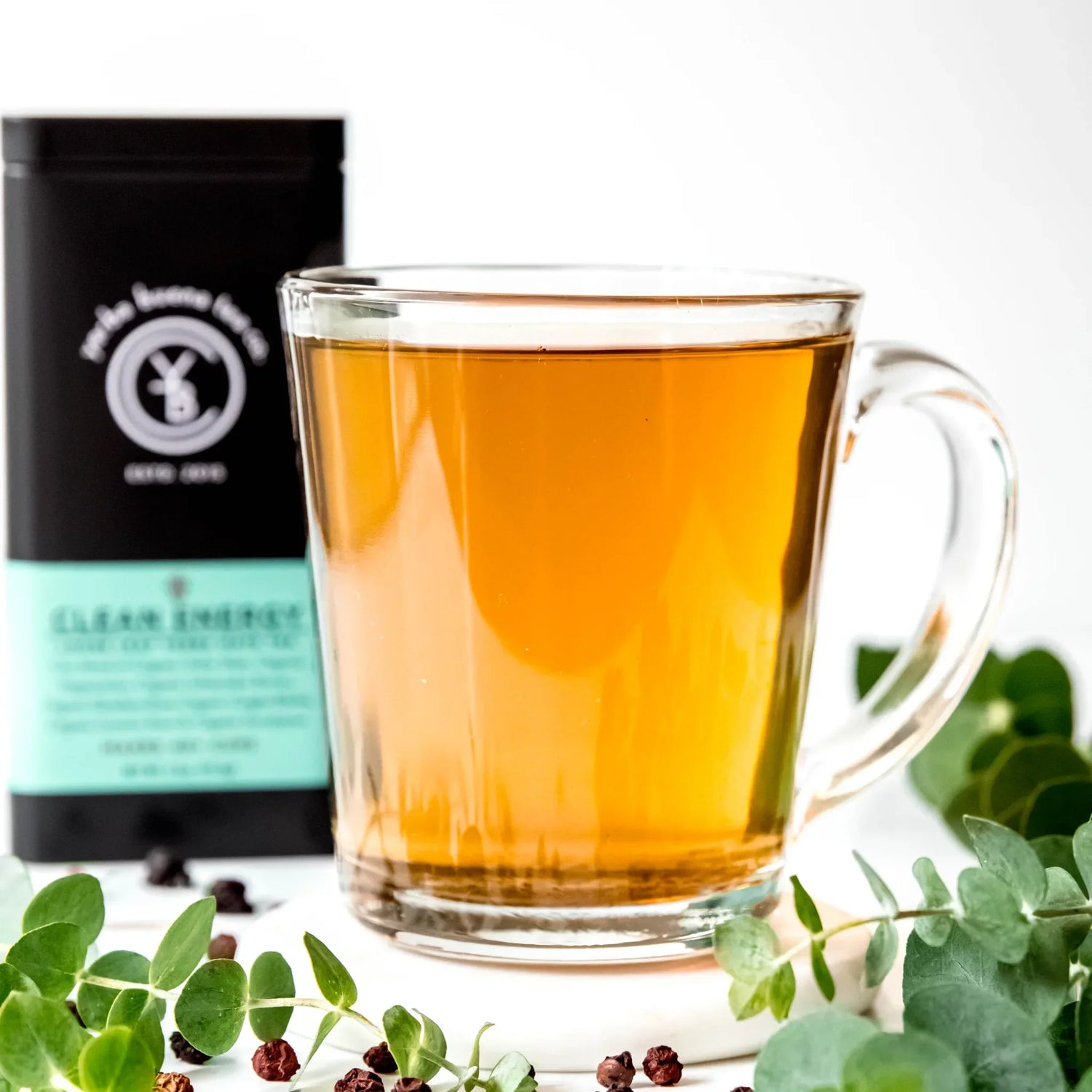 A glass mug of brewed organic yerba mate beside a Yerba Buena Tea Co. Clean Energy tin