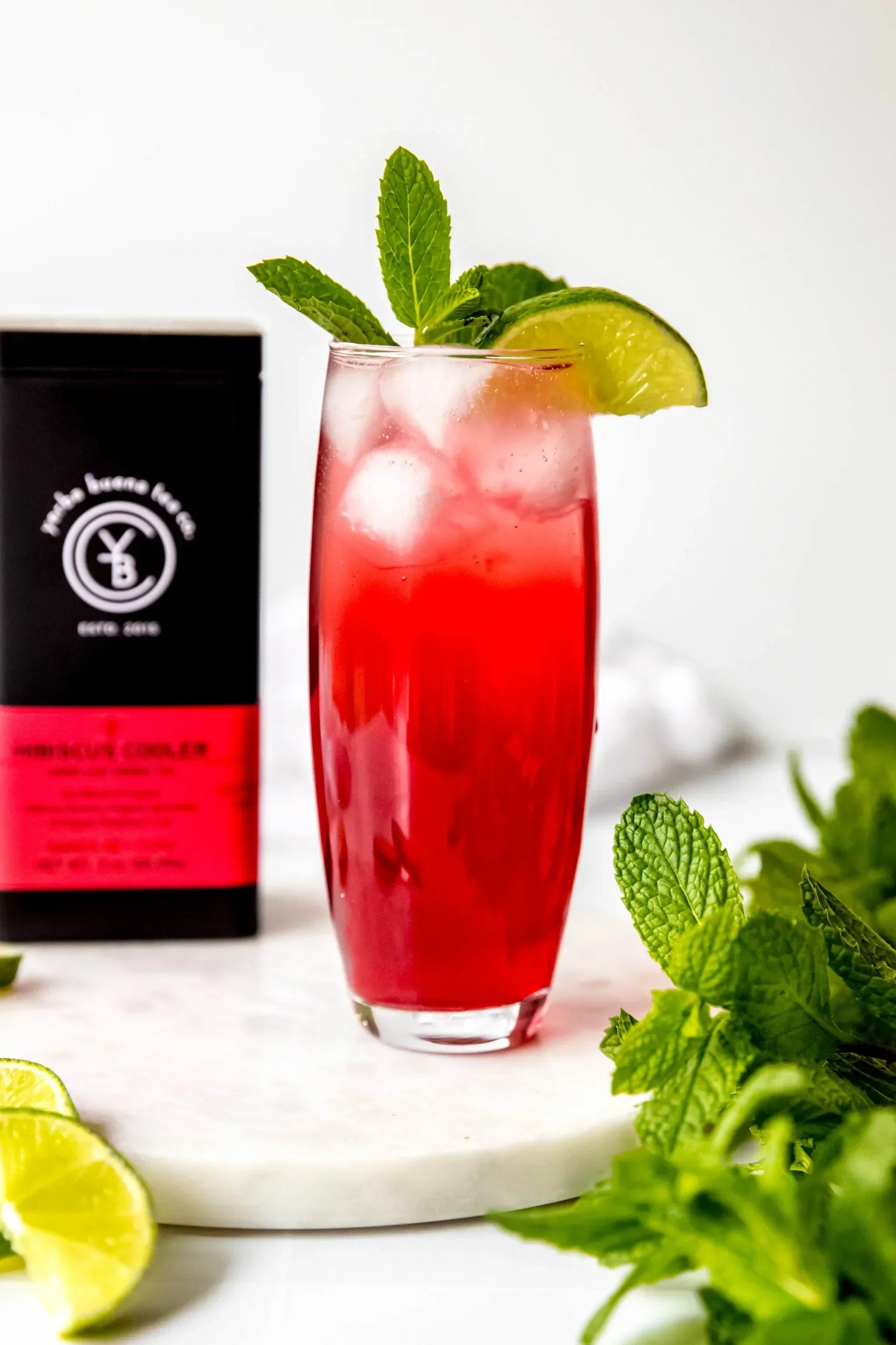 Iced hibiscus lime mocktail garnished with fresh mint and lime, made with organic hibiscus tea by Yerba Buena Tea Co.