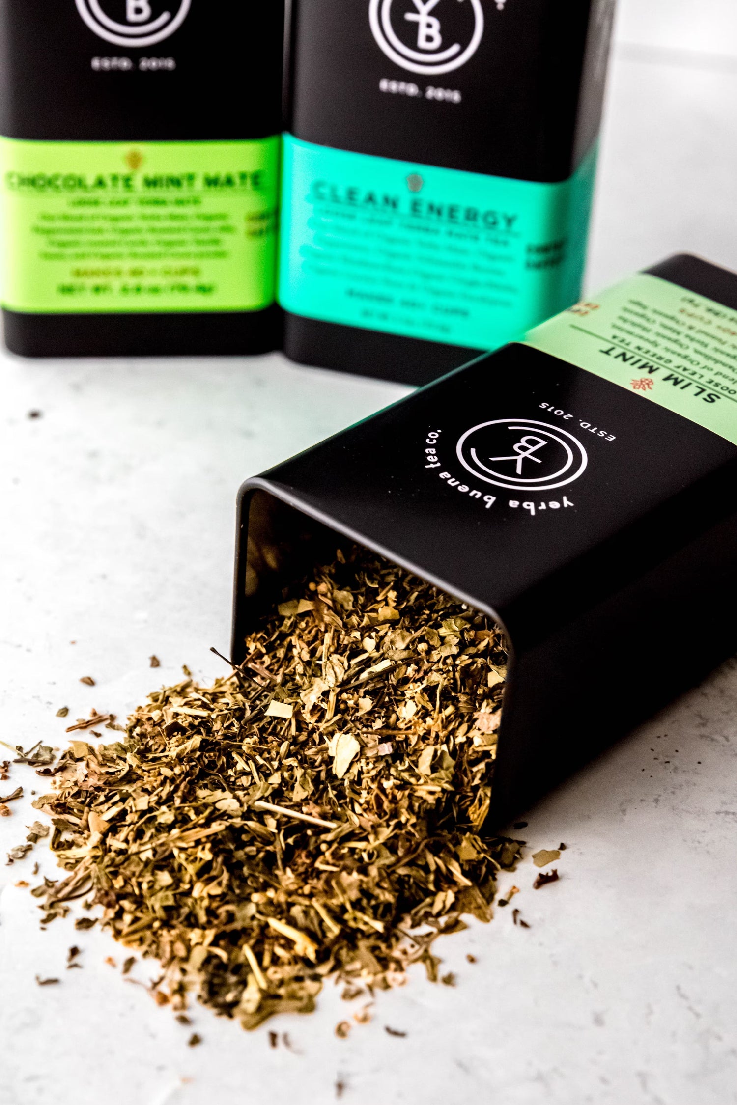 Vibrant organic loose leaf yerba mate spilling from a Yerba Buena Tea Co. tin.