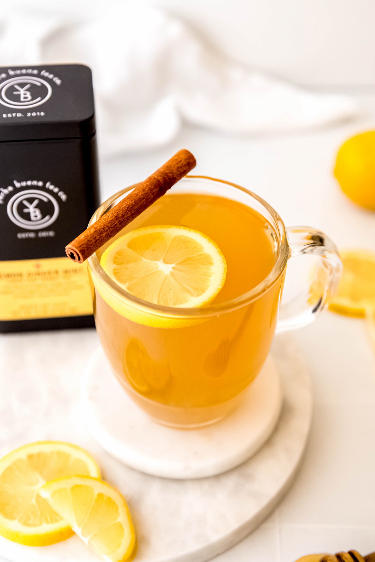 Warm lemon ginger hot toddy garnished with lemon slices and a cinnamon stick, brewed from organic Lemon Ginger Mint tea by Yerba Buena Tea Co.