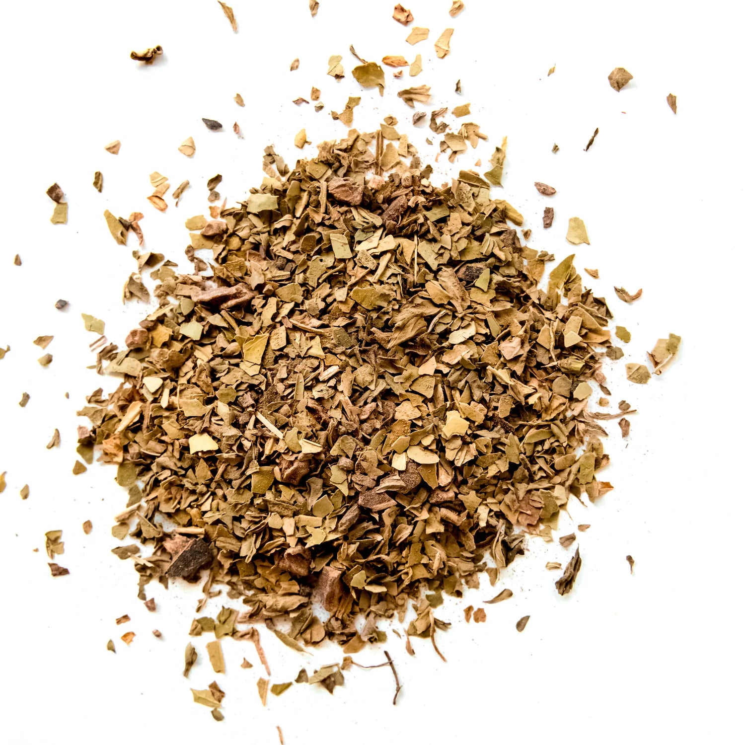 Loose leaf Chocolate Mint Mate tea blend with dried herb pieces scattered on white background, by Yerba Buena Tea Company.