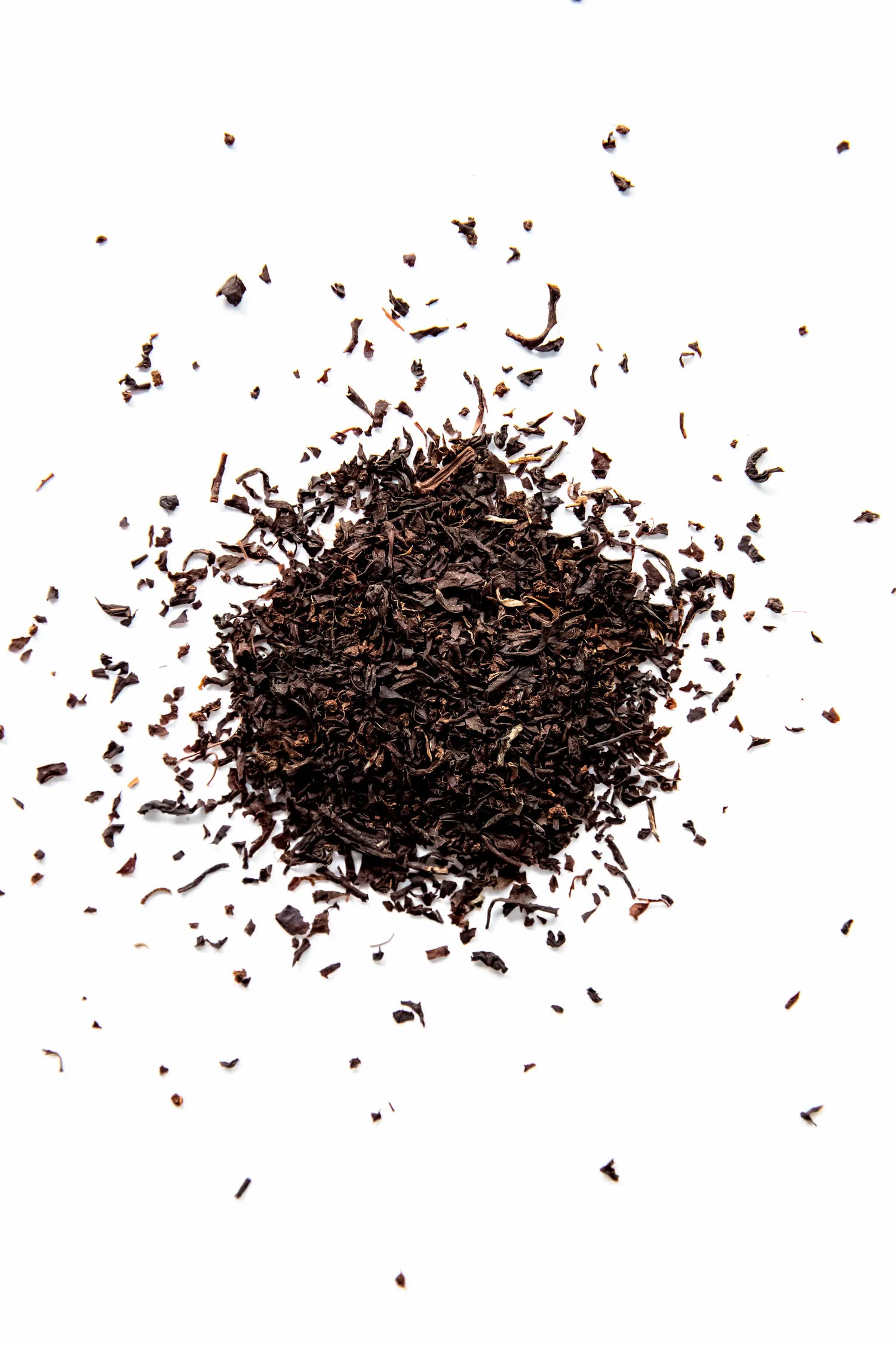 A close-up top-down view of Yerba Buena Tea Co. Irish Breakfast loose leaf black tea, showing a pile of dark, finely cut organic black tea leaves on a white surface.