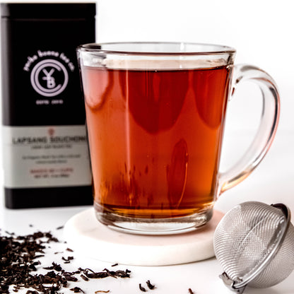 A cup of brewed Lapsang Souchong tea with a deep amber hue, exuding a robust smoky aroma.