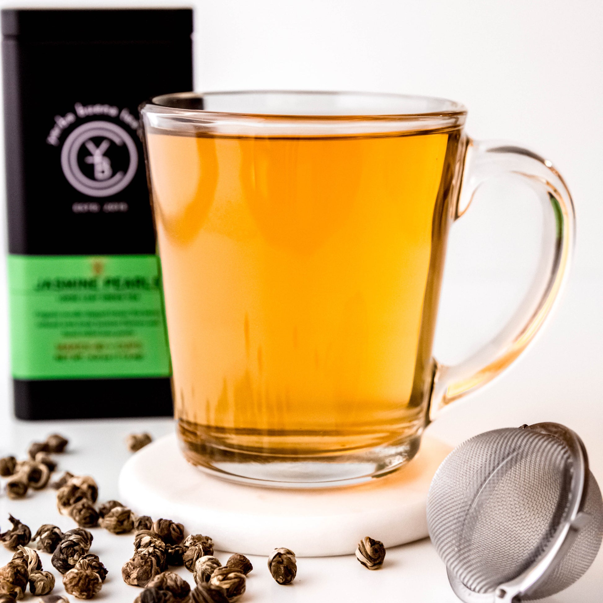 A cup of brewed Jasmine Pearls tea with a light golden hue, exuding a delicate floral aroma.