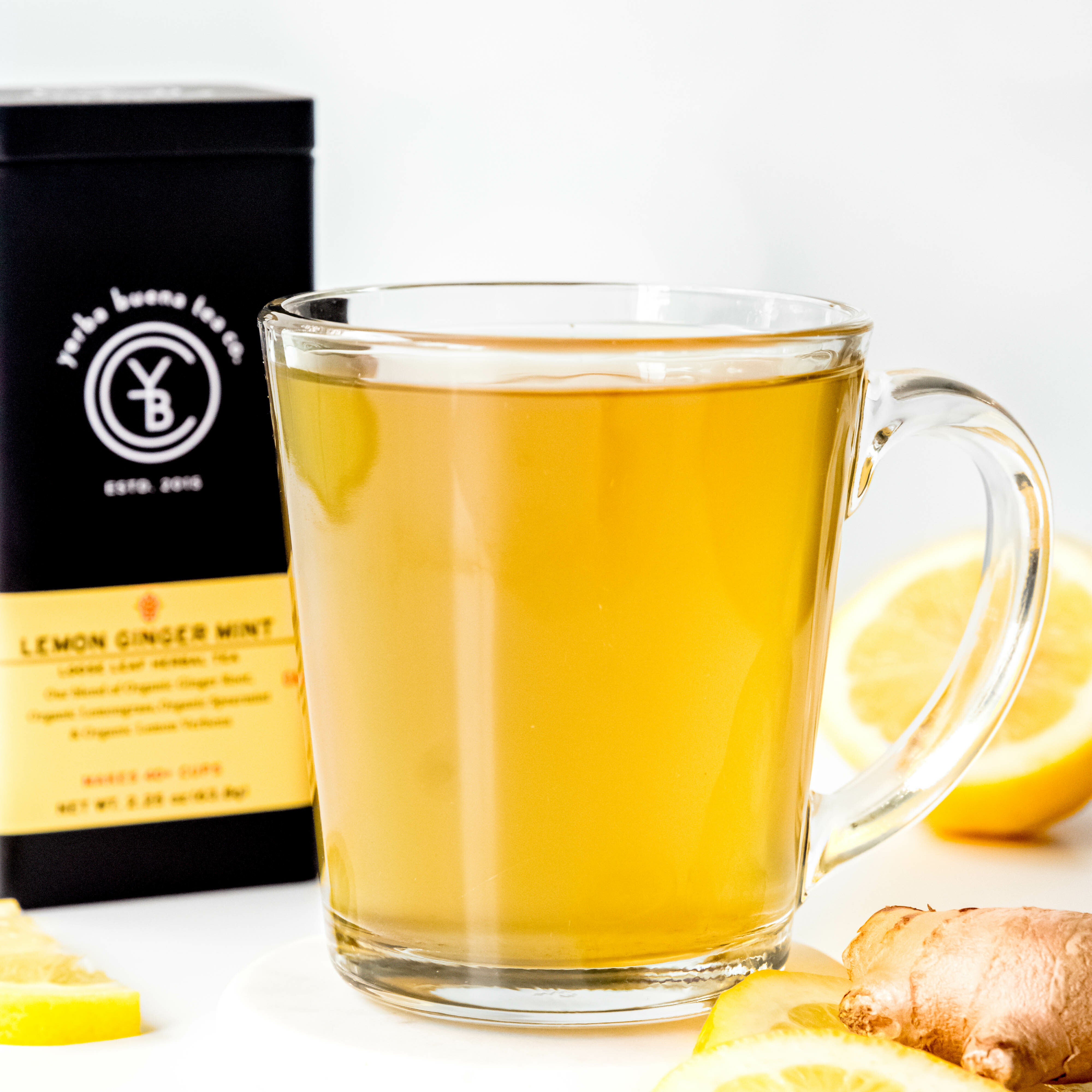 A cup of brewed Lemon Ginger Mint tea from Yerba Buena Tea Co. A vibrant, caffeine-free herbal blend with organic ginger root, lemongrass, spearmint, and lemon verbena.