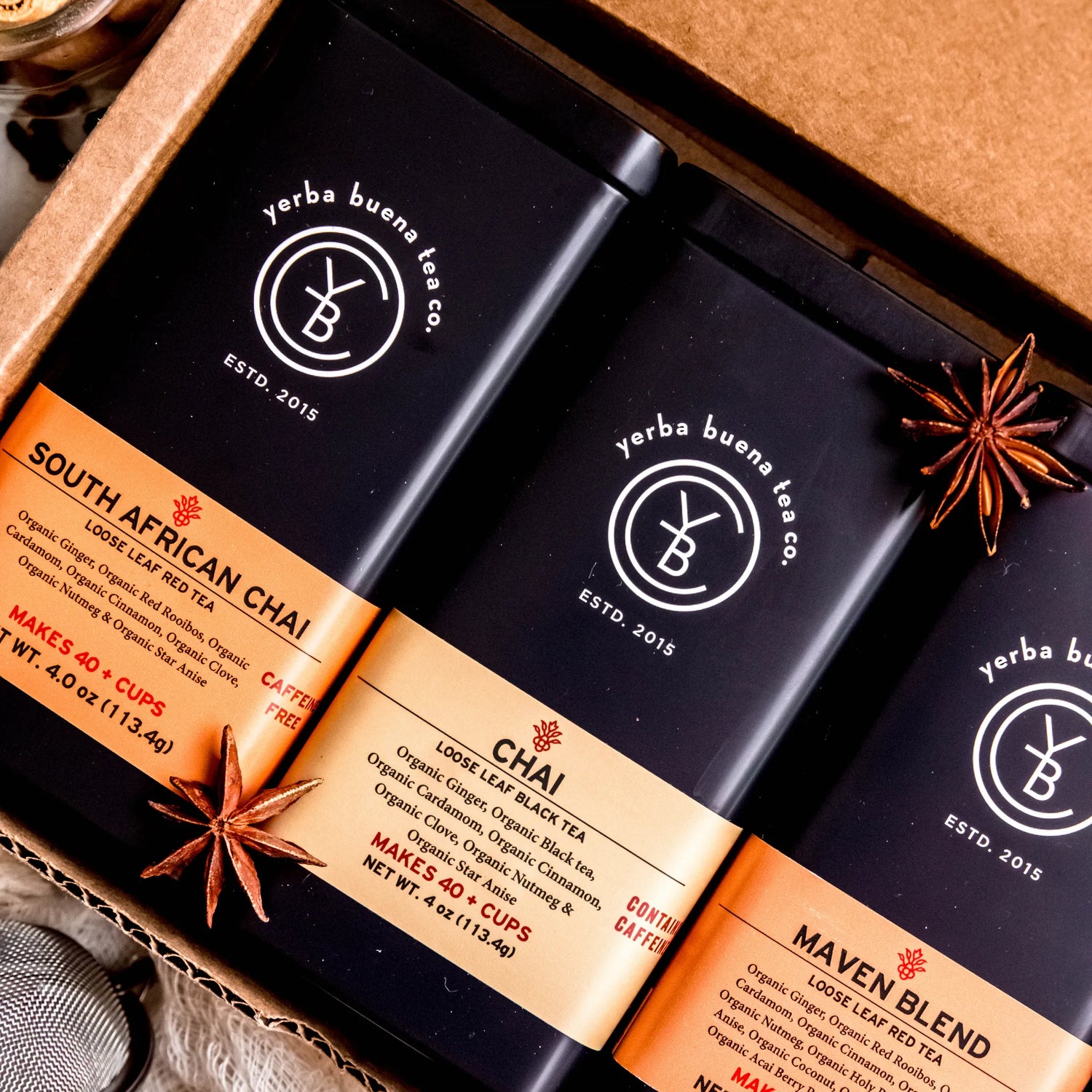 The Chai Box gift set with three loose leaf tea pouches: South African Chai, Chai, and Maven Blend, arranged with star anise on a cork surface, by Yerba Buena Tea Company.