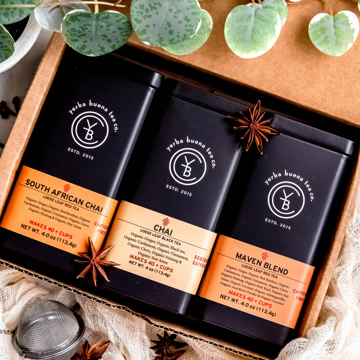 The Chai Box gift set with three loose leaf tea pouches: South African Chai, Chai, and Maven Blend, arranged in a wooden box with star anise and greenery, by Yerba Buena Tea Company.