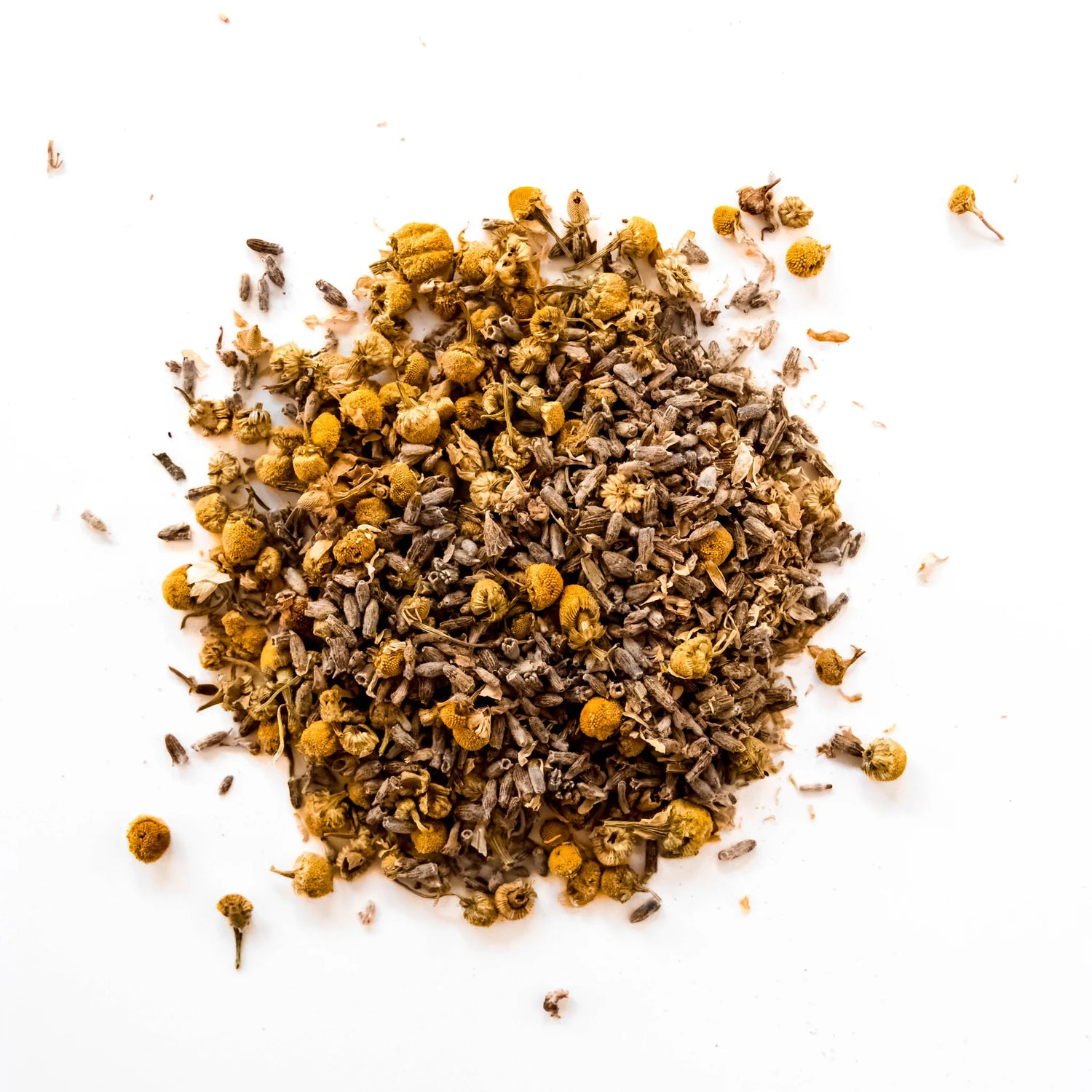 Loose leaf chamomile lavender herbal tea blend with dried chamomile flowers and herbal pieces scattered on white background, by Yerba Buena Tea Company.