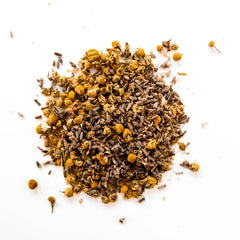 Loose leaf chamomile lavender herbal tea blend with dried chamomile flowers and herbal pieces scattered on white background, by Yerba Buena Tea Company.