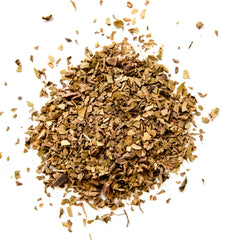Loose leaf Chocolate Mint Mate tea blend with dried herb pieces scattered on white background, by Yerba Buena Tea Company.
