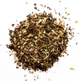Loose leaf herbal tea blend with dried herbs and plant material scattered on white background, by Yerba Buena Tea Company.