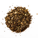 Loose leaf herbal detox tea blend with dried herbs and botanicals scattered on white background, by Yerba Buena Tea Company.