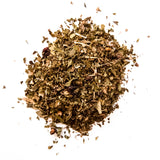 Loose leaf herbal tea blend with dried herbs and botanicals scattered on white background, by Yerba Buena Tea Company.