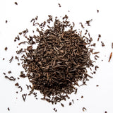 Loose leaf English Breakfast black tea with curled leaves scattered on white background, by Yerba Buena Tea Company.