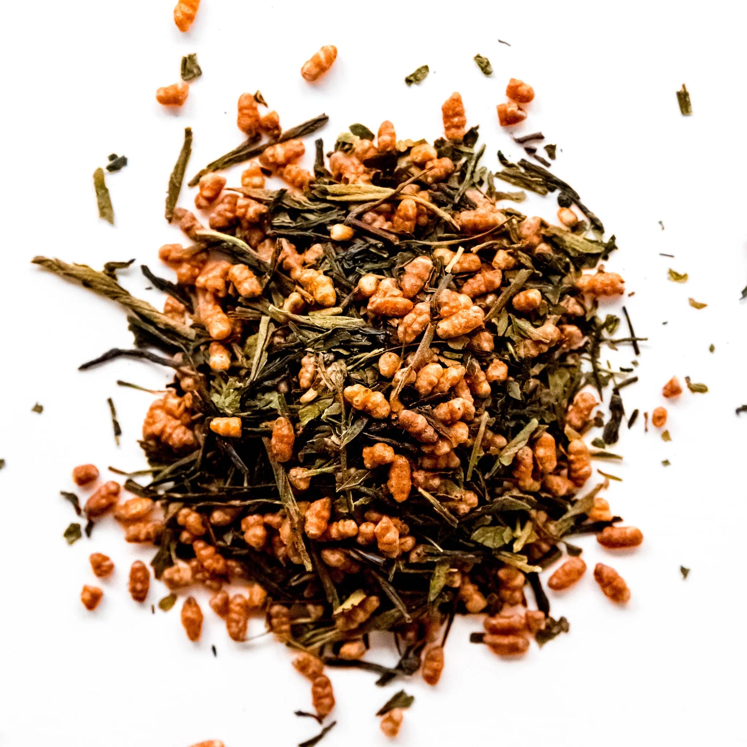 Loose leaf genmaicha tea blend with green tea leaves and roasted rice kernels scattered on white background, by Yerba Buena Tea Company.