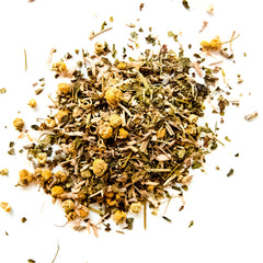 Loose leaf herbal tea blend with chamomile flowers and mint scattered on white background, by Yerba Buena Tea Company.