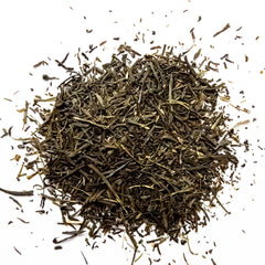 Loose leaf green sencha tea scattered on white background in natural dried leaf form, by Yerba Buena Tea Company.