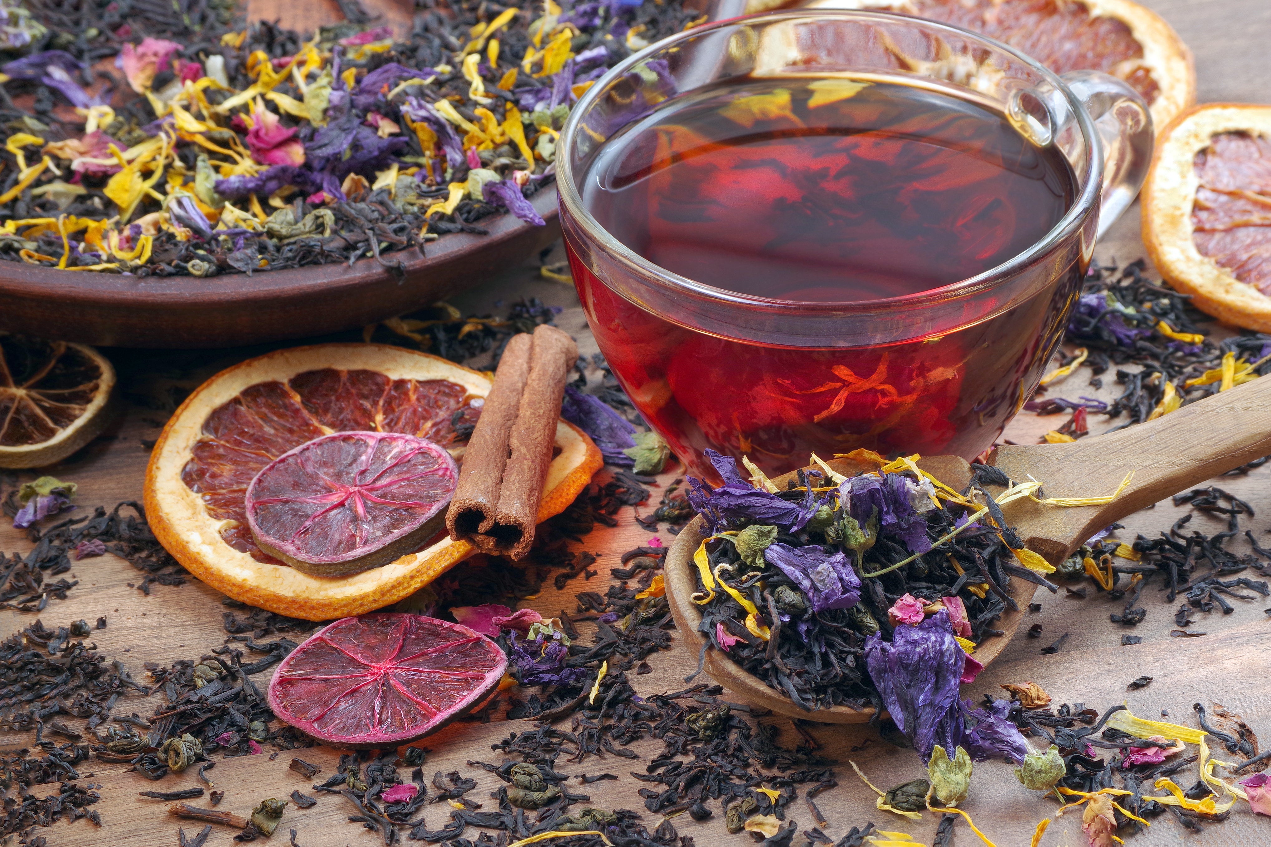 A cup of herbal tea surrounded by dried citrus slices, cinnamon sticks, and loose leaf herbs from Yerba Buena Tea Co.