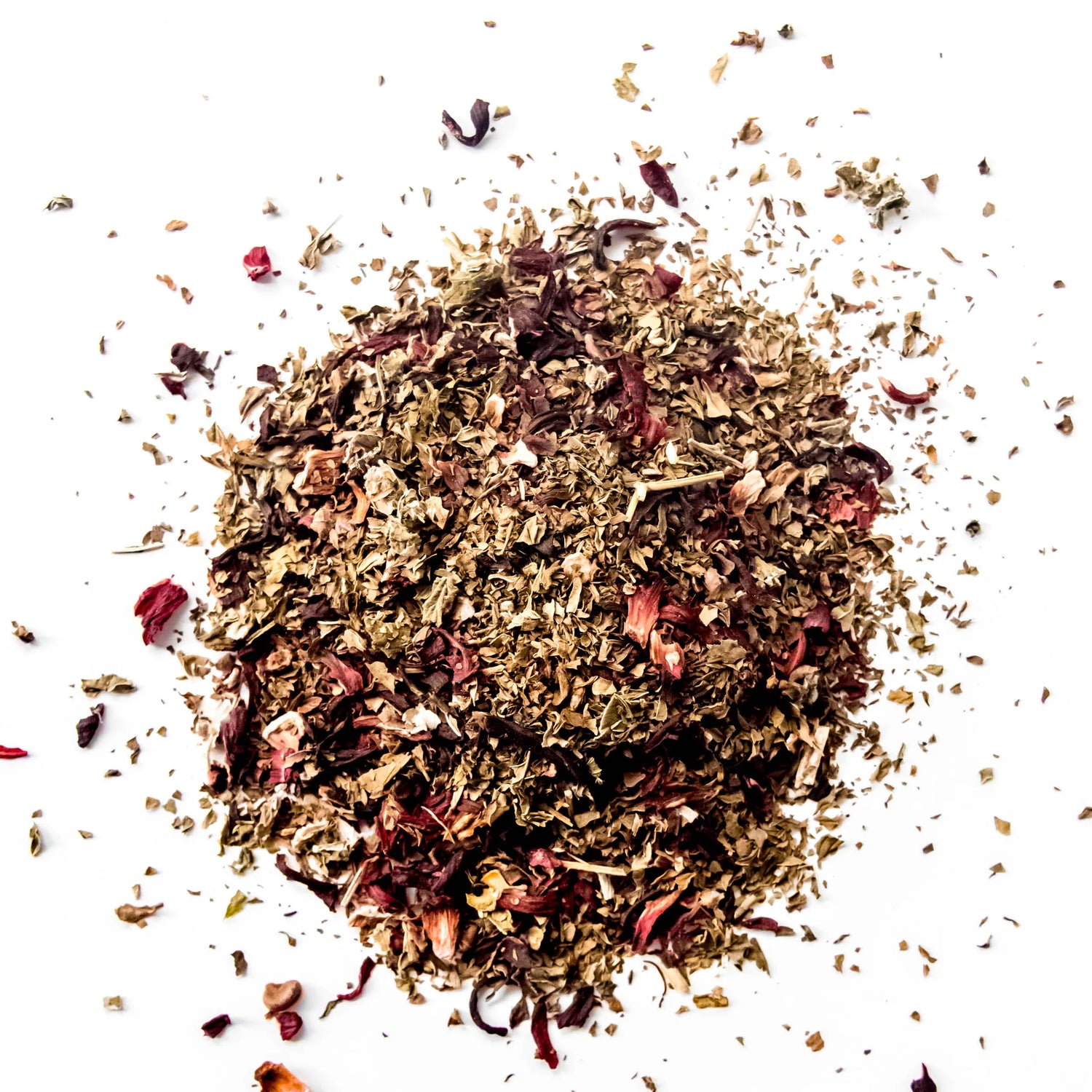 Loose leaf herbal tea blend with dried hibiscus petals and golden herbs scattered on white background, by Yerba Buena Tea Company.