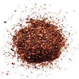 Loose leaf Honey Rooibos red tea scattered on white background in pile, by Yerba Buena Tea Company.