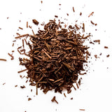 Loose leaf houjicha tea with roasted brown pieces scattered on white background, by Yerba Buena Tea Company.