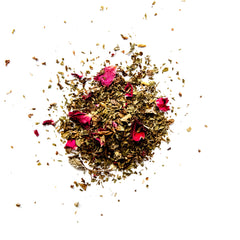 Loose leaf herbal tea blend with dried green mate, pink rose petals, and scattered leaves on white background, by Yerba Buena Tea Company.