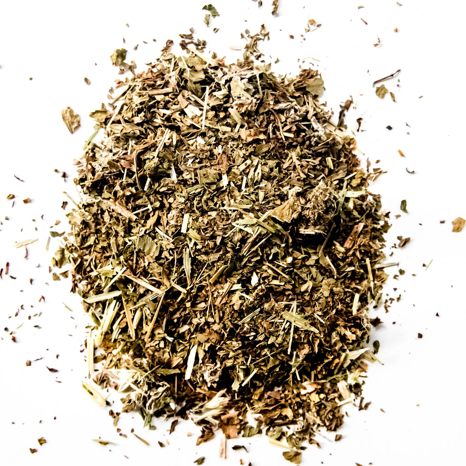 Loose leaf herbal tea blend with dried herbs and plant material scattered on white background, by Yerba Buena Tea Company.