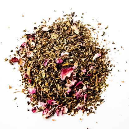 A close-up of the loose leaf blend of Skin Glow tea, showing the finely chopped organic spearmint, peppermint, red clover, rosehips, hibiscus, roses, elderflowers, and calendula flowers against a white background.