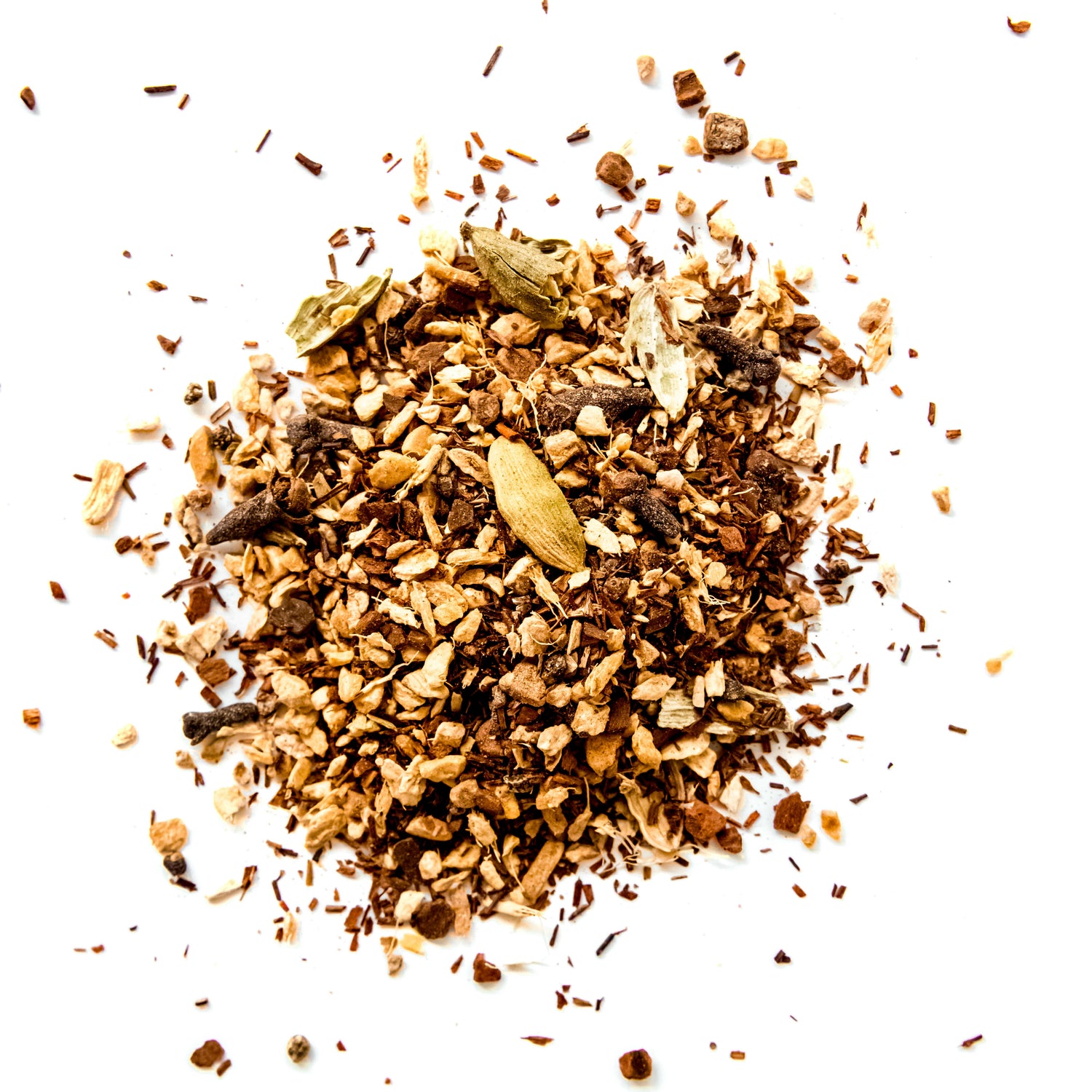 A close-up of the loose leaf blend of South African Chai tea, showing the finely chopped organic red rooibos, ginger root, cinnamon, cardamom, cloves, and nutmeg against a white background.