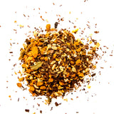 Loose leaf herbal tea blend with turmeric, spices, and dried citrus scattered on white background, by Yerba Buena Tea Company.